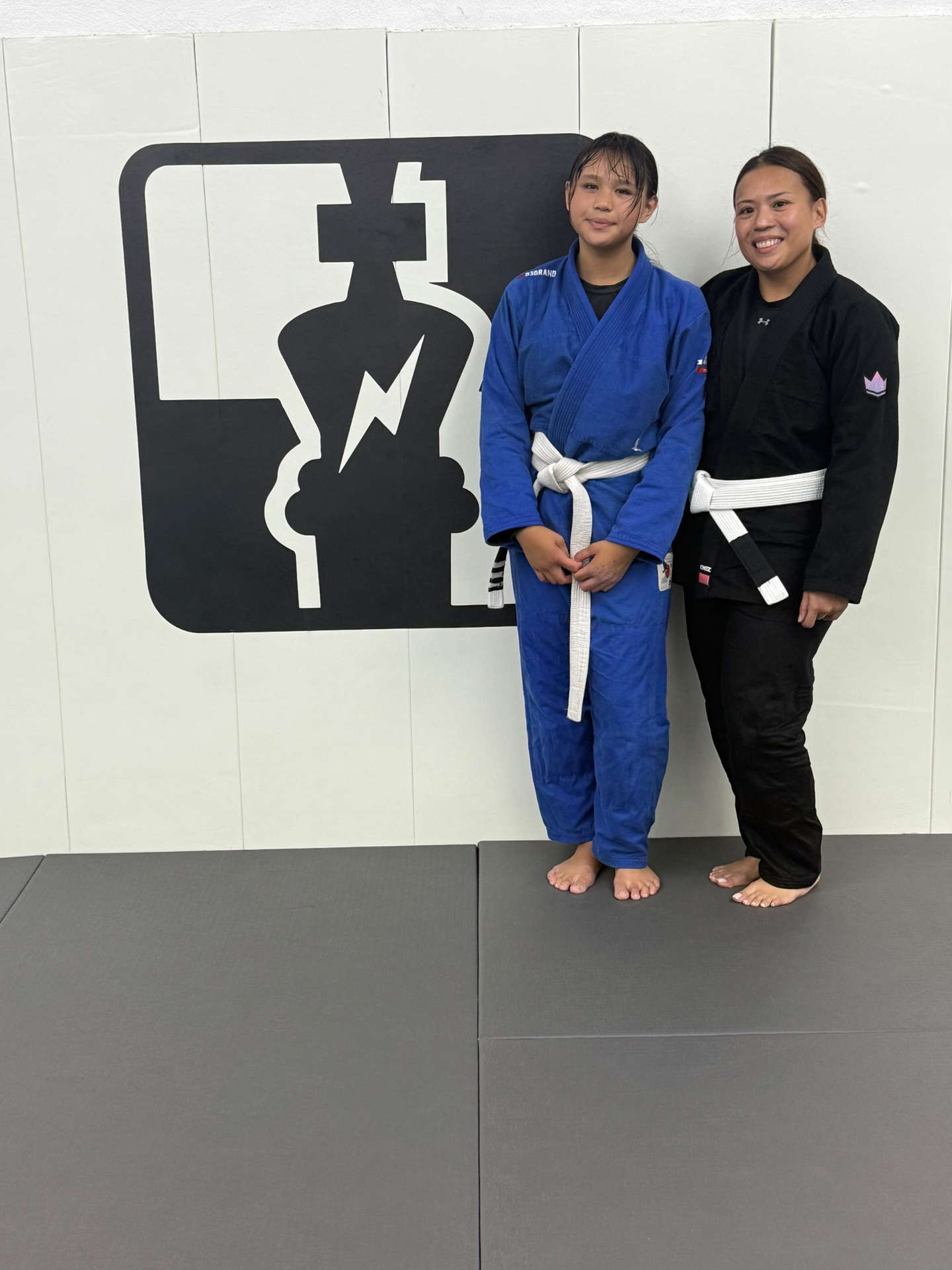 Sophia Miranda with a teammate in front of the GUMA logo wall